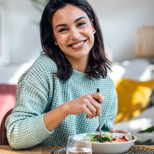 Woman smiling while eating healthy meal at home