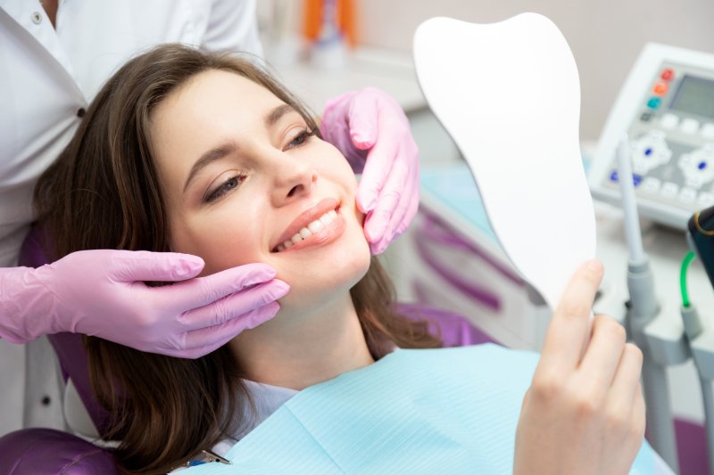 a patient checking her smile with a mirror